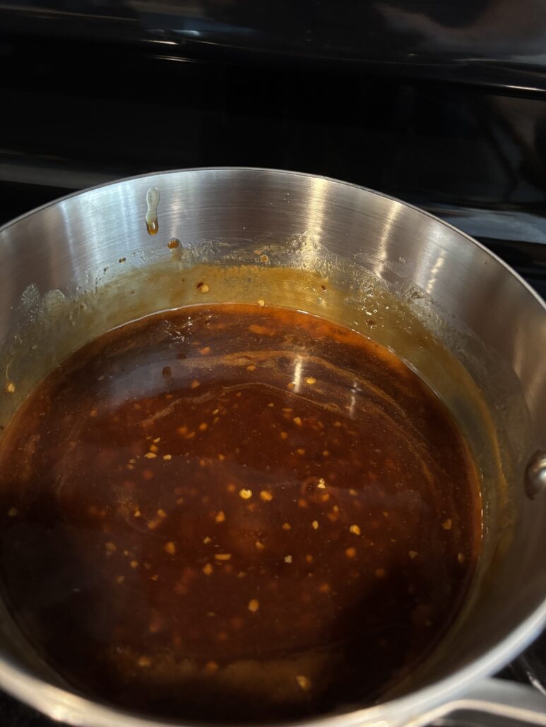 Thick honey soy glaze coating the inside of a saucepan, ready to toss with wings