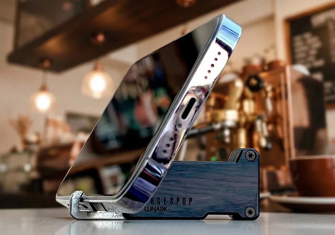 LUNARK Edge & Pop Dual EDC knife with both sliders closed, propped up as a phone stand on a coffee shop counter